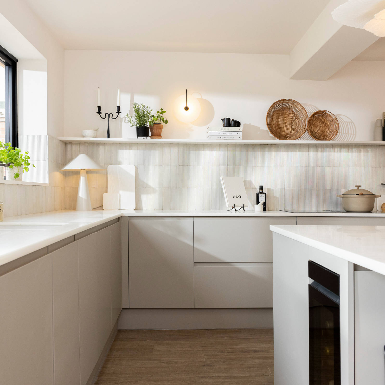 View of Yasmin Wyatt's open, light and airy neutral shade handleless Luna kitchen from Magnet, a white Corian worktop in Onyx, wine fridge integrated into kitchen island.
