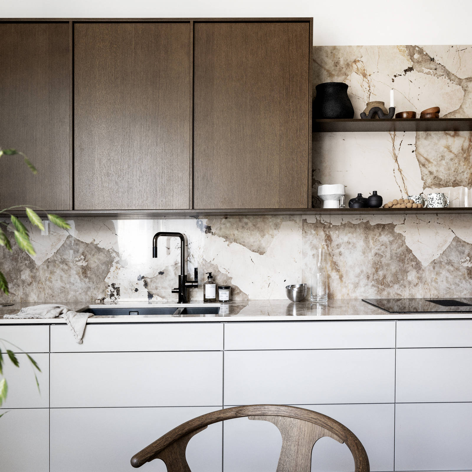 Kjøkken med kombinasjon av kjøkkenbenk i beige Line Korn med overskap i Favn finert eikedør i brunbeis fra Sigdal, benkeplate og sprutbak som matcher, og åpne vegghyller i brunbeiset eikefiner.