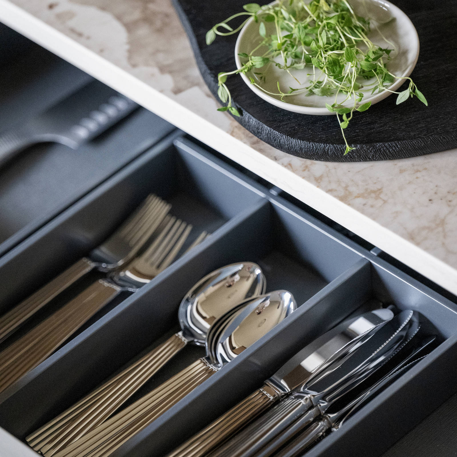 Uttrekkbar kjøkkenskuff i det beige kjøkkenet Arkitekt pluss Sand fra Sigdal, med grå bestikkinnlegg.