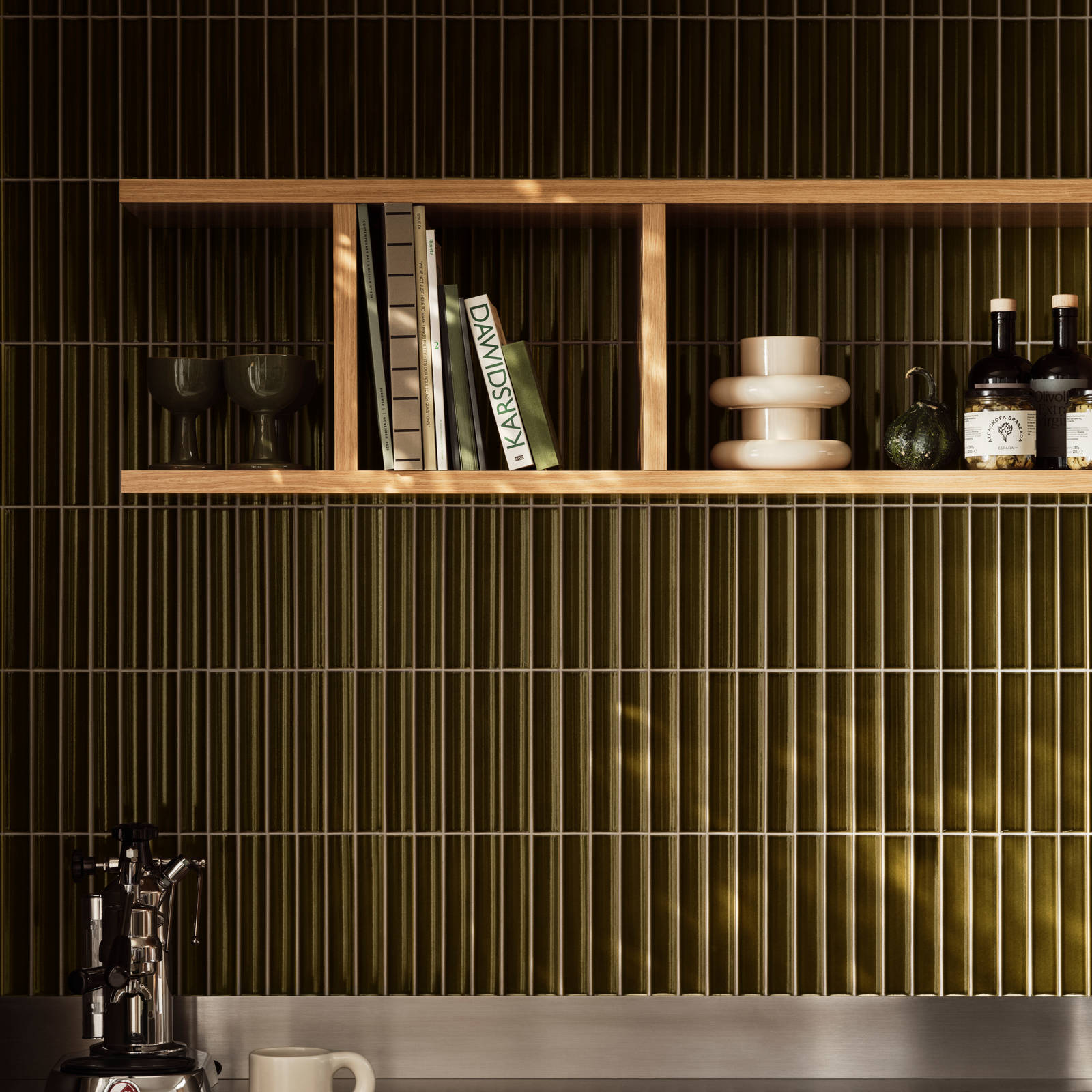 Eg væghylder over grønne skabe med grønne fliser i Jubilæumskøkken fra INVITA inspireret av 1970'erne