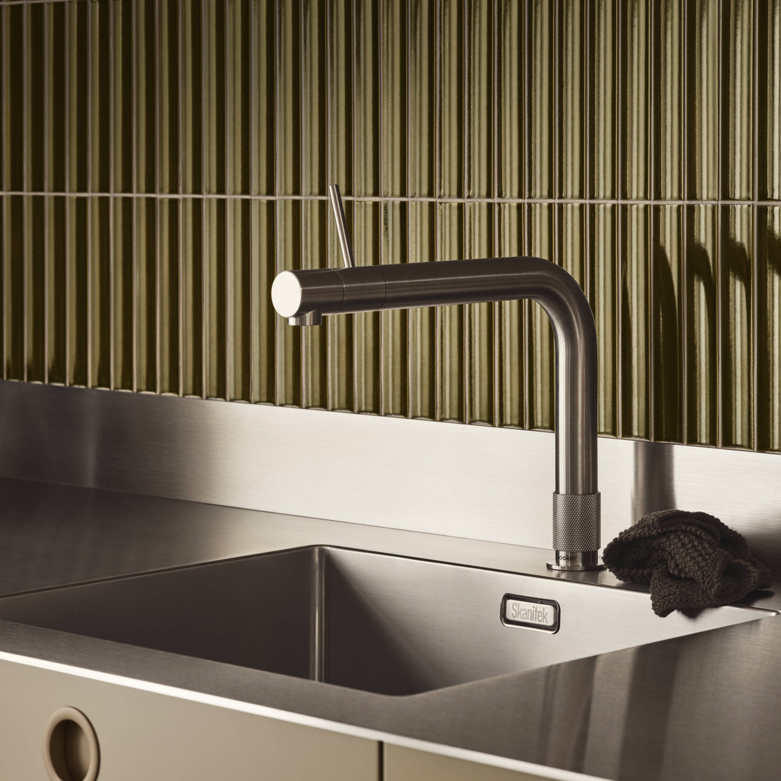 Nærbilllede av rustfrit stål vask og armatur i Jubilæumskøkken fra INVITA med grønne skaber inspireret av 1970'erne