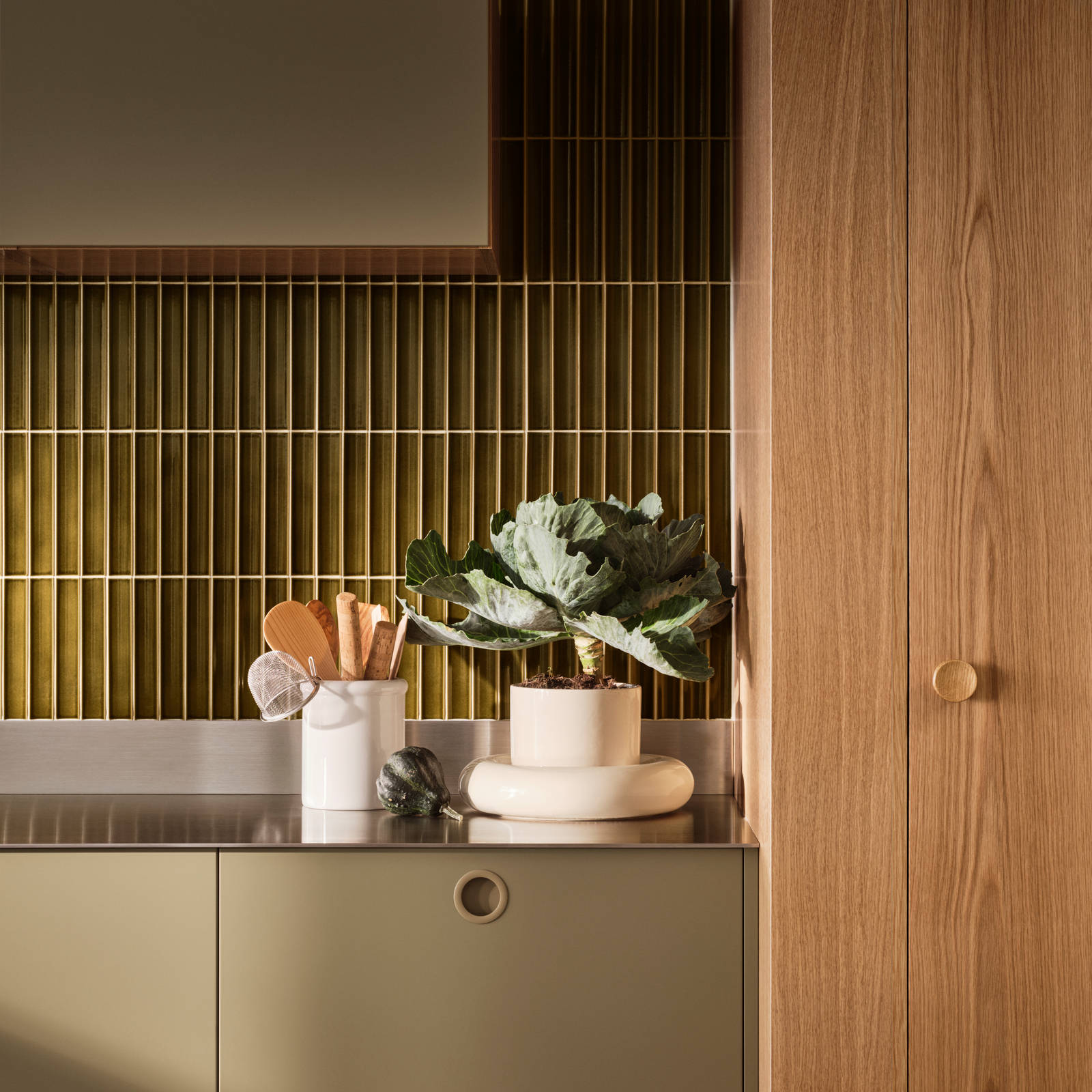 Jubilæumskøkken fra INVITA med træfinér eg, matchende vægpanel og grønne skaber inspireret av 1970'erne med infræsede greb