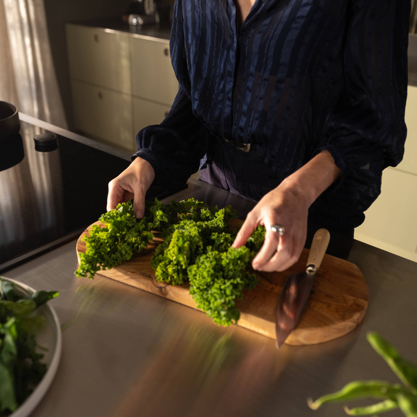 Nærbillede af en, der skærer grønkål op på et skærebræt