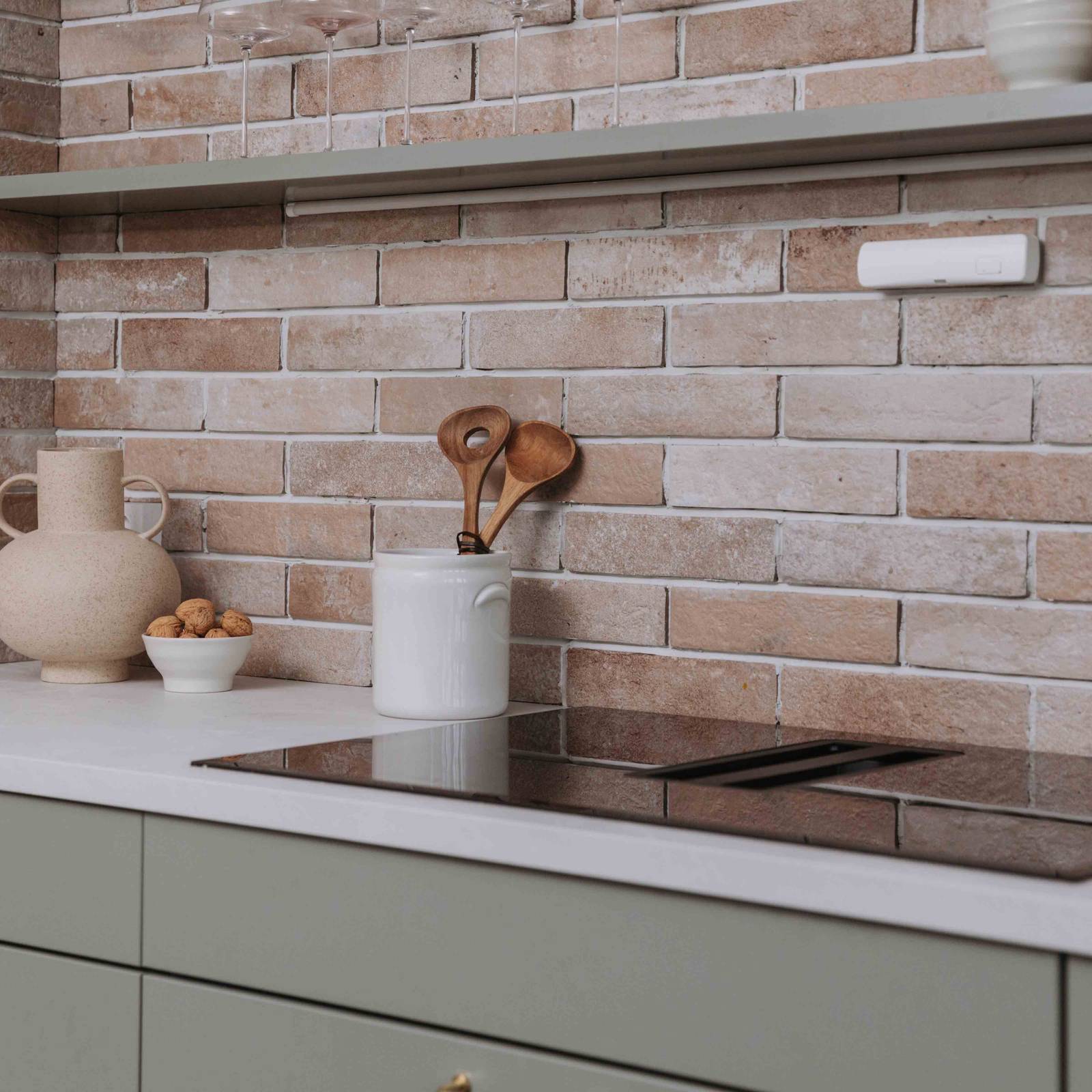 Keramikk og kjøkkenutstyr av tre på kjøkkenbenken ved induksjonstopp i Stine Hartmanns Uno Furu kjøkken fra Sigdal med laminat Kandia marmor og teglstein-flis