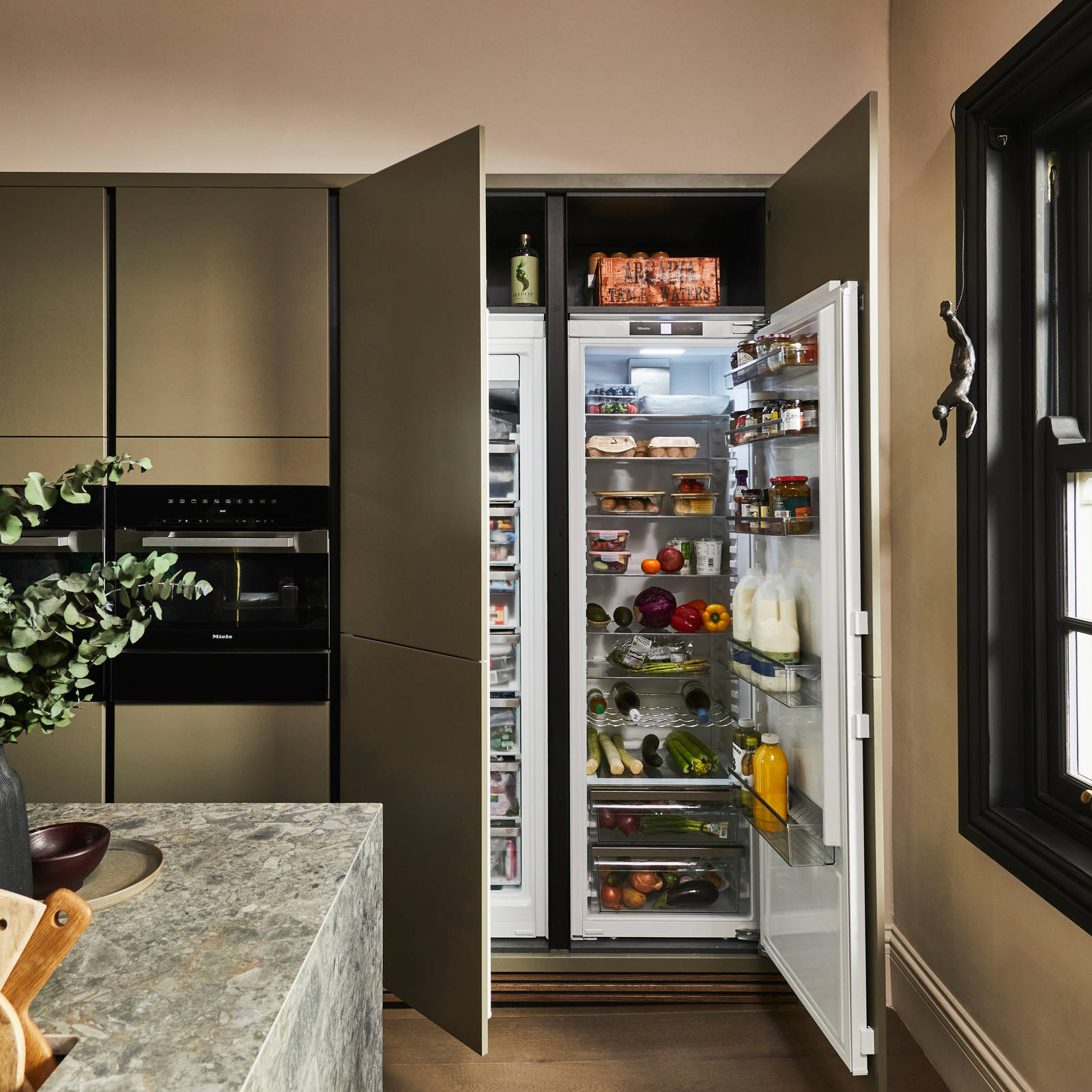 Wide open integrated double refridgerators in Soho Balmoral Cabinets, with a view of the corner of the Dekton worktop-covered kitchen island in the foreground.