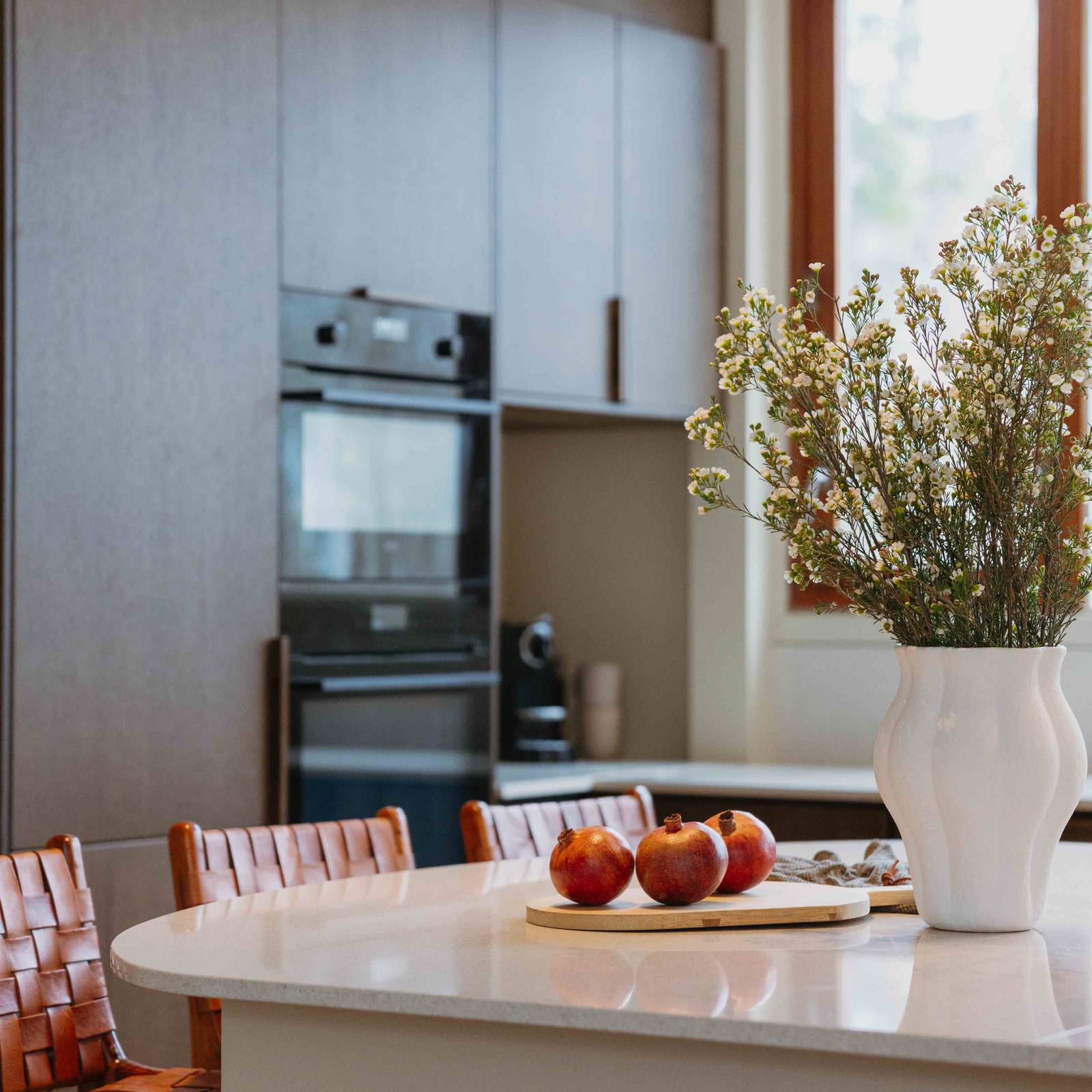 Eikekjøkkenet Favn fra Sigdal i beisfargen Nøtt kjøkkenøy og ovner i høyskaber, matchende tre håndtag, med benkeplate Blanco City fra Silestone.