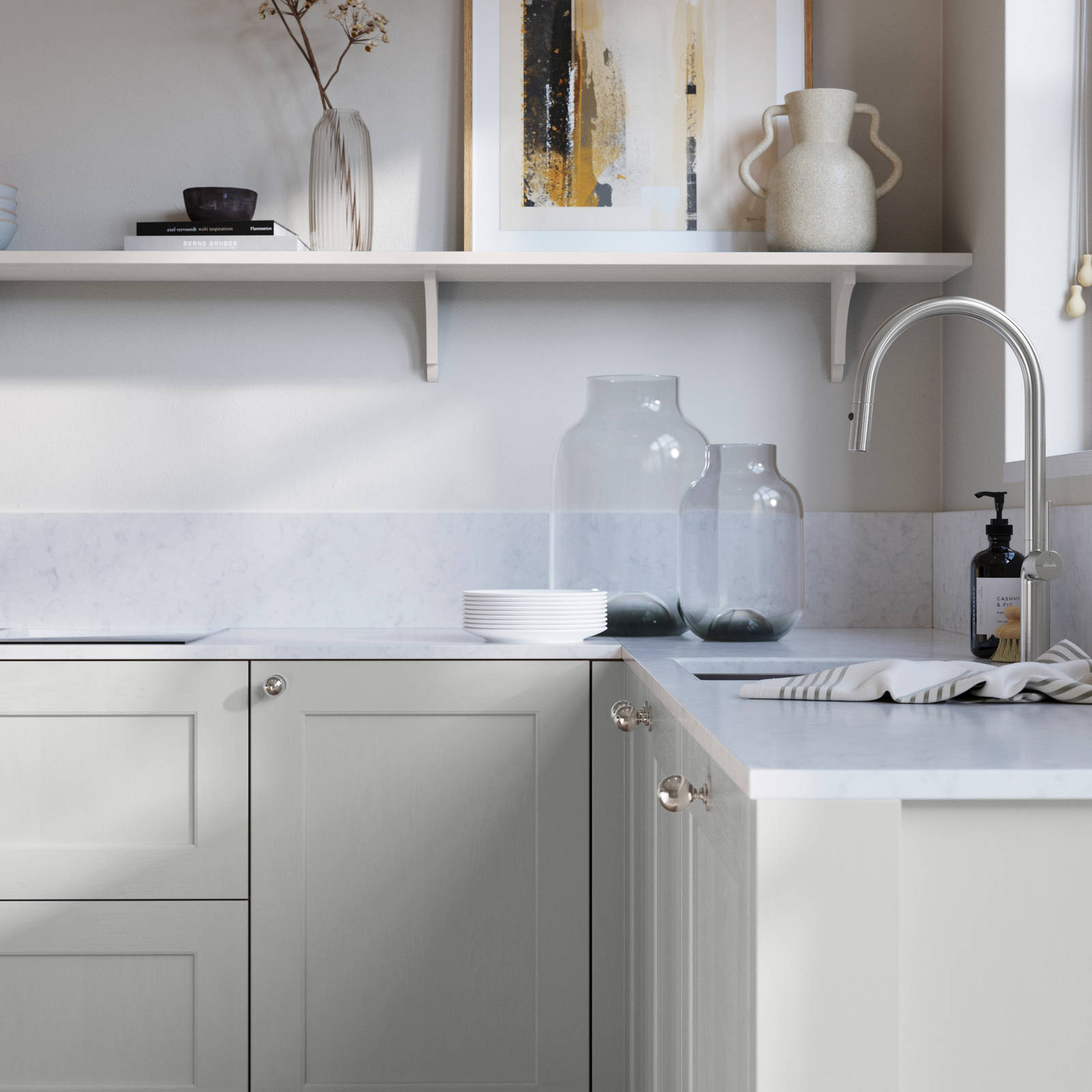 Ludlow, a traditional Shaker-style premium feel kitchen range with a visible woodgrain on its panelled doors here shown in the light shade Washed cotton styled with steel knobs, steel tap, a white marbled worktop with matching splashback.