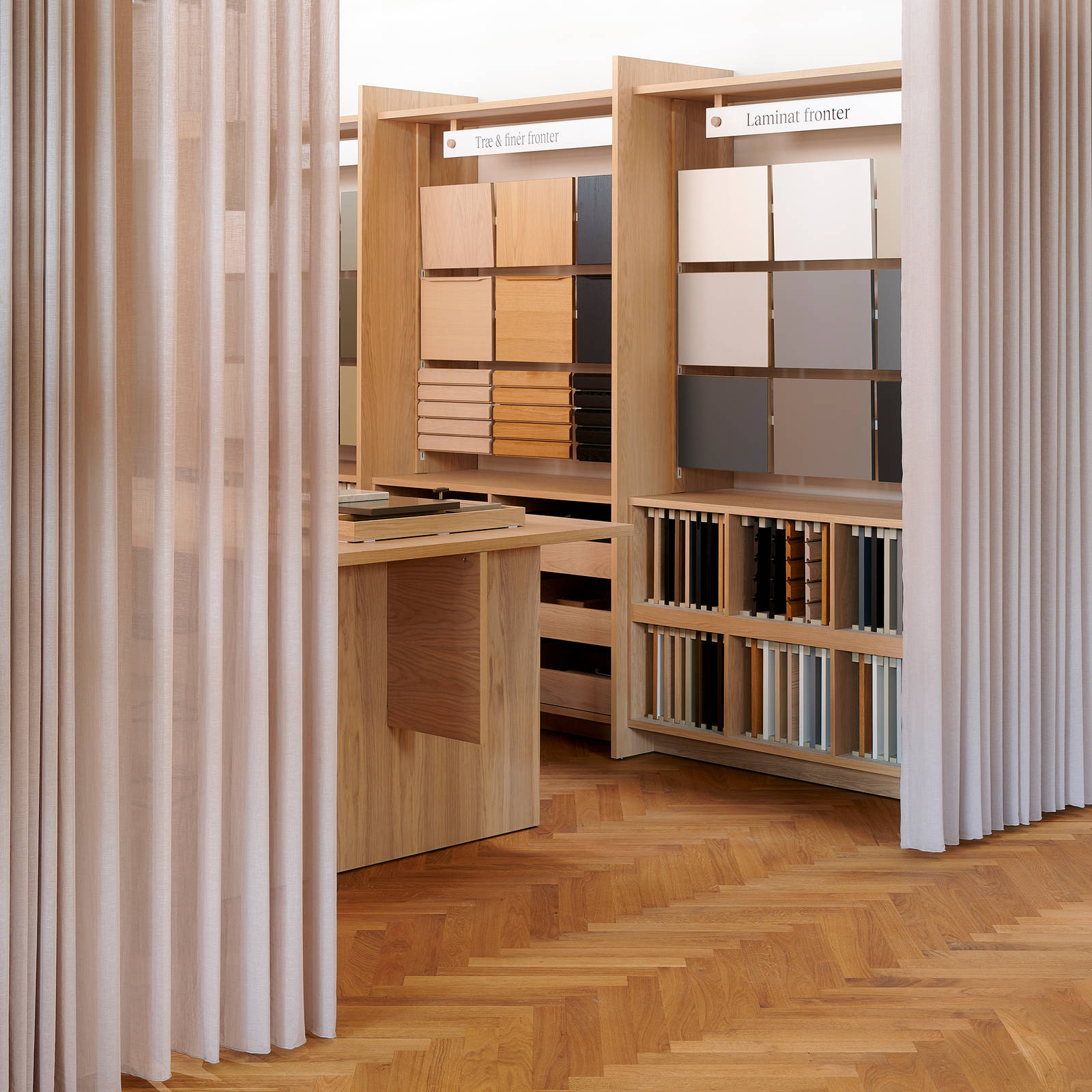 Væghylder med prøver af køkkenlåger i forskellige stilarter og farver i INVITAs butik