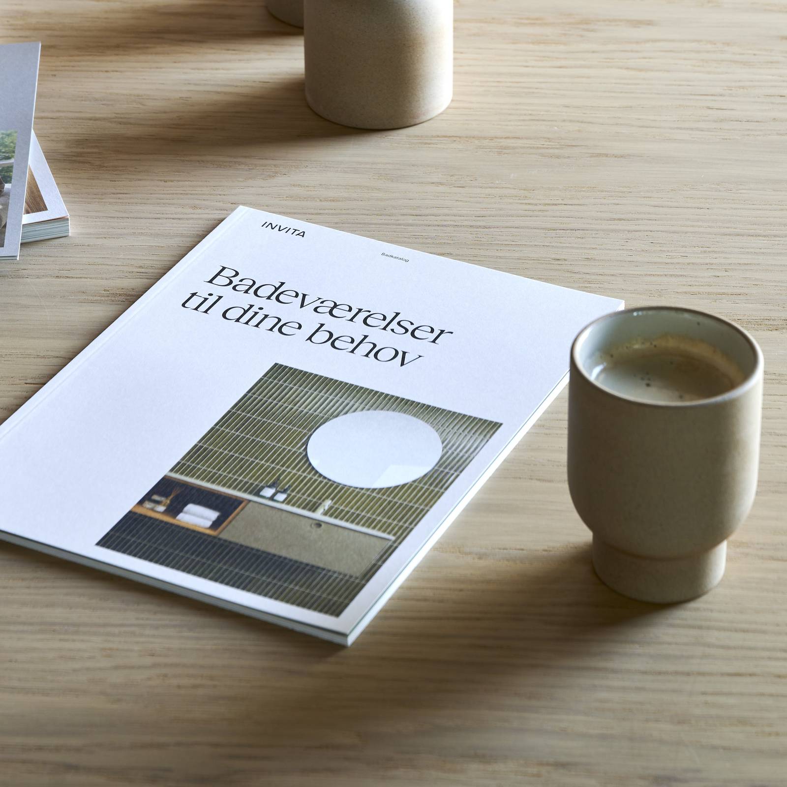 Træbord i INVITAs butik med kaffekopper og katalog