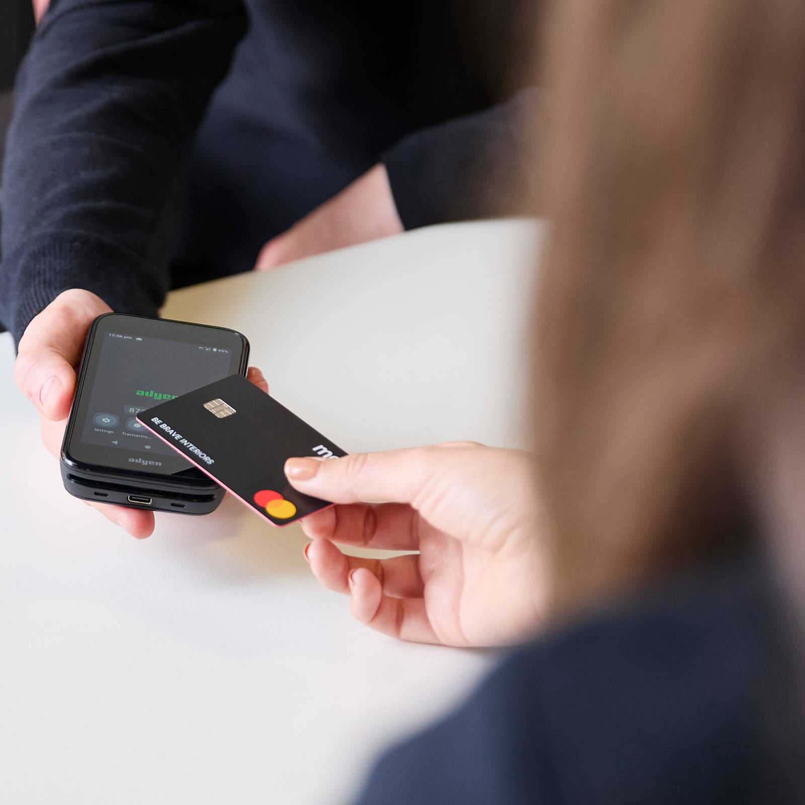 Close-up of customer holding a credit card over a smartphone held by Magnet colleague for payment at Magnet store