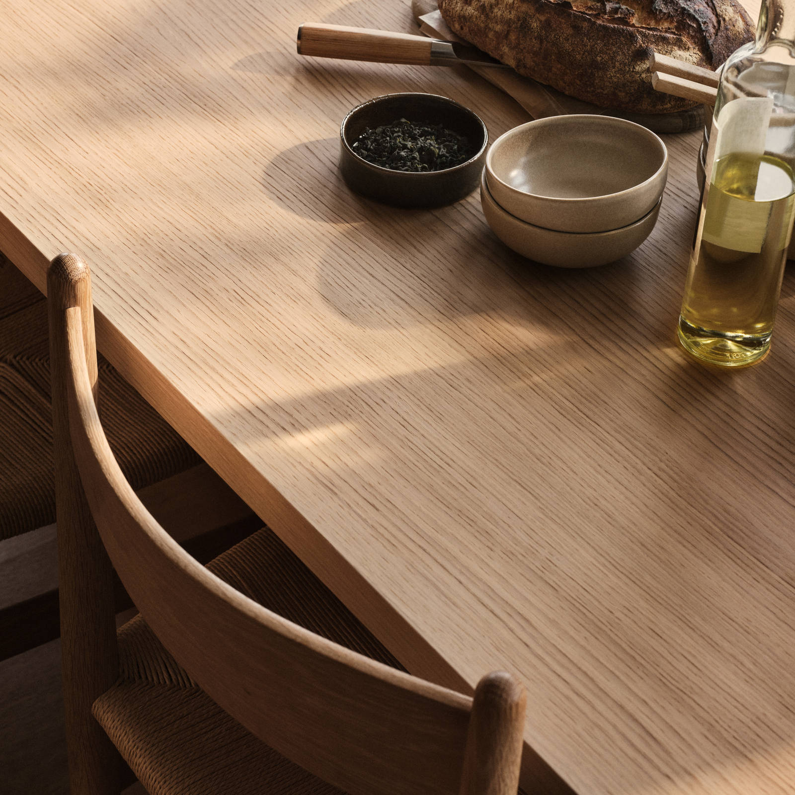 Bord och stol i trä med keramik och en flaska olivolja