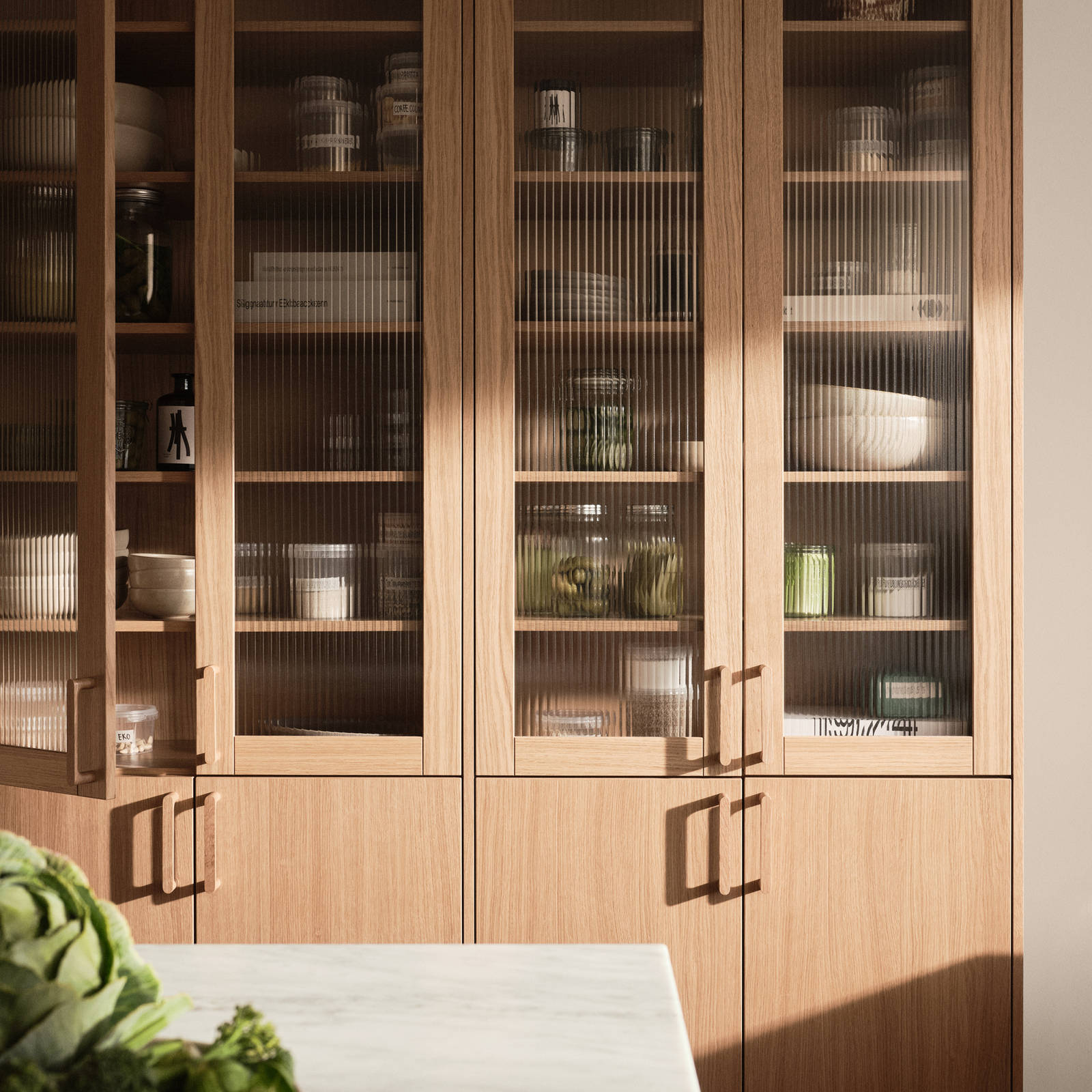 Siri Barjes kök Ekbacken från Marbodal, högskåp med ekluckor och vitrinluckor med ram i ek, matchande handtag i trä, köksö.