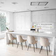 Valkoinen keittiö, jossa perinteiset maalatut karmiovet, messinkikahvat ja marmoroitu työtaso, keittiösaareke istuimilla.