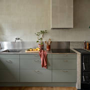 Inredningsprofilen Svante Öquists kök från Marbodal, Arkitekt Plus i den gröna kulören Tall med rostfri bänkskiva i kombination med kvartsit, handtag i krom. Vedspis och induktionshäll.