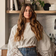 Siri Barje iklädd en ljus stor blus och jeans i sitt kök från Marbodal.