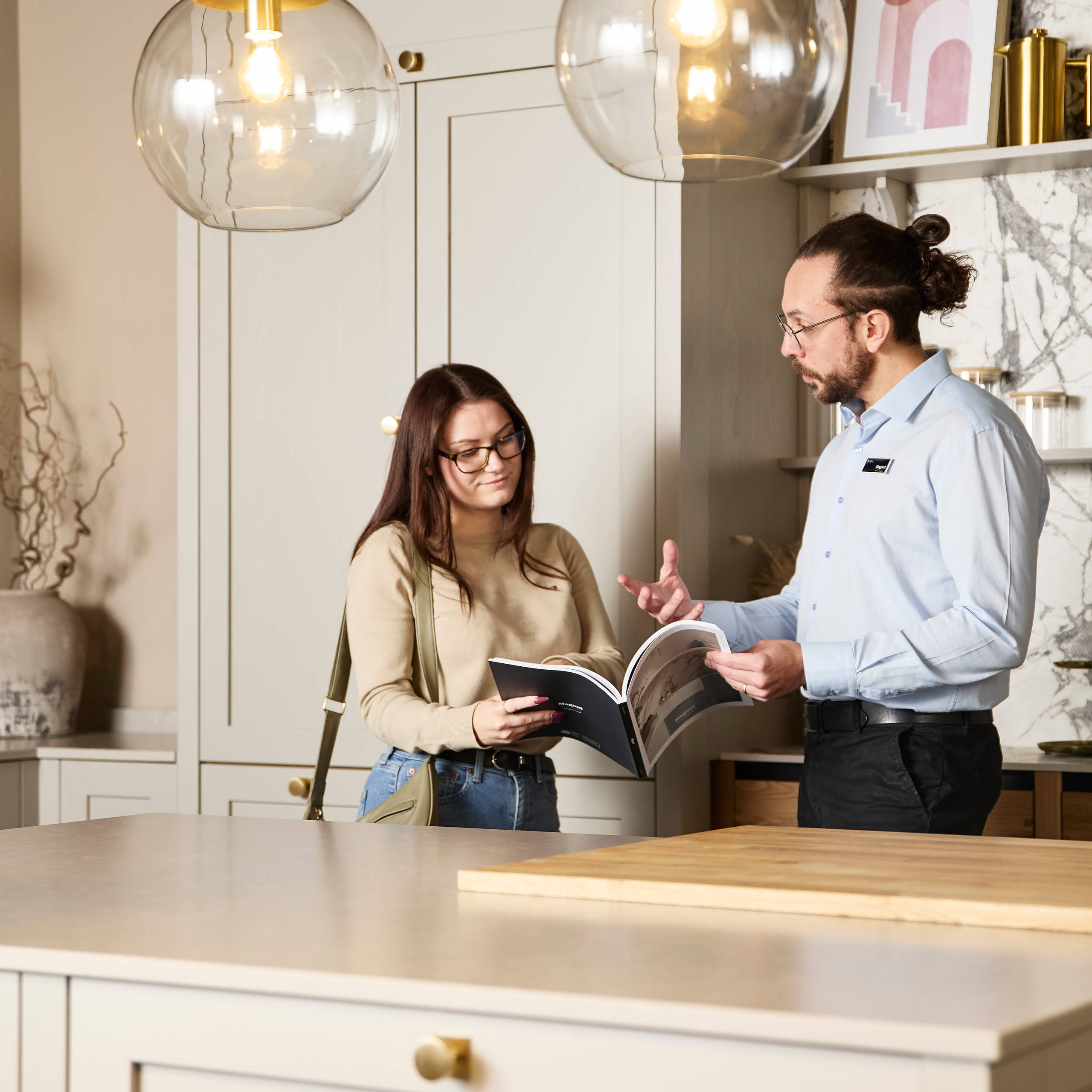 Woman and kitchen designer looking at and discussing a brochure in Shaker style kitchen at a Magnet Showroom.