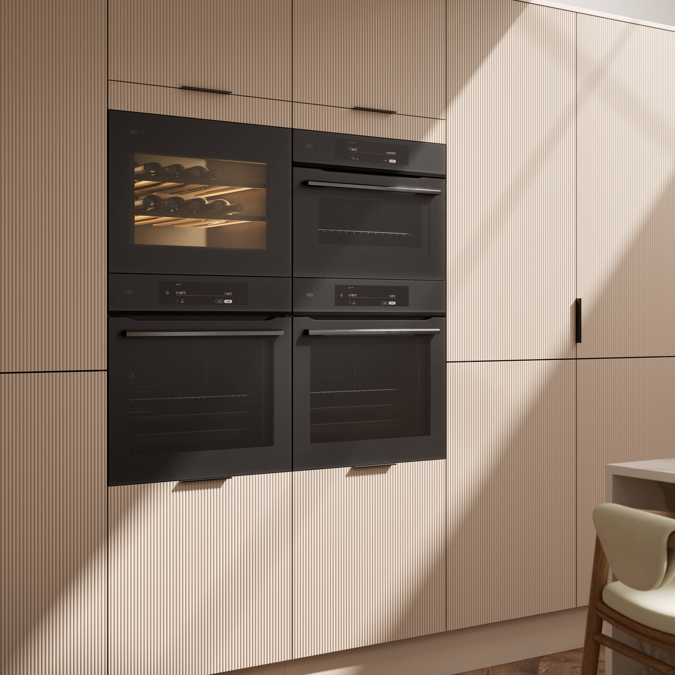 Fluted front kitchen Reed from Magnet in light warm neutral shade Shell, tall cabinets with appliances like ovens and a wine cooler, black handles