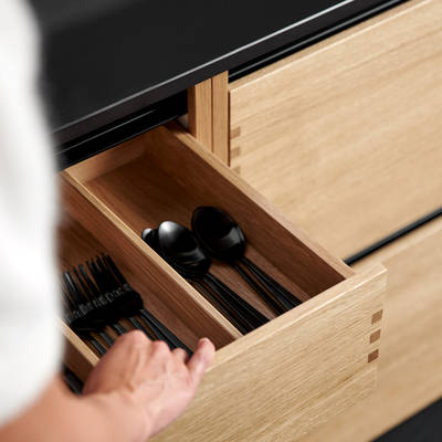 Nærbild av køkken Glød fra INVITA, åben bestikskuffe i massivt egetræ med fingertappede samlinger  og sort granit bordplade