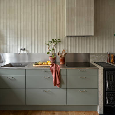 Inredningsprofilen Svante Öquists kök från Marbodal, Arkitekt Plus i den gröna kulören Tall med rostfri bänkskiva i kombination med kvartsit, handtag i krom. Vedspis och induktionshäll.