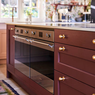 Parallell view of Sophie Robinson's maximalist kitchen, two Smeg ovens integrated into the Ludlow Burlington red kitchen island from Magnet.