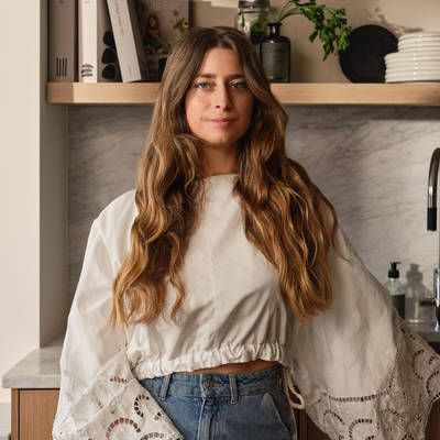 Siri Barje iklädd en ljus stor blus och jeans i sitt kök från Marbodal.