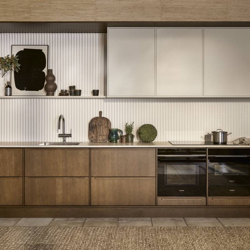 Mørk eg køkkenbænk Forever Oak fra INVITA kombineret med overskaber Athena Sand, hvide fliser, bordplade og massiv ek håndtag, ovn og dampovn fra Siemens