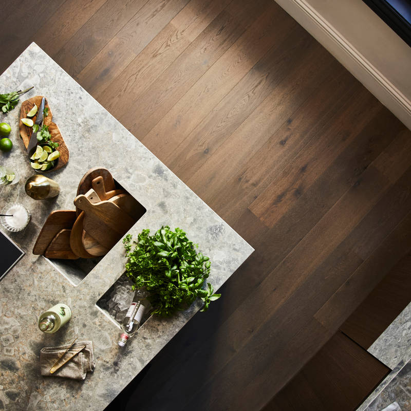 Birds eye view of kitchen island with Dekton in Ceppo worktop,wooden cutting boards with cut up lime fruits and a large plant of basil.