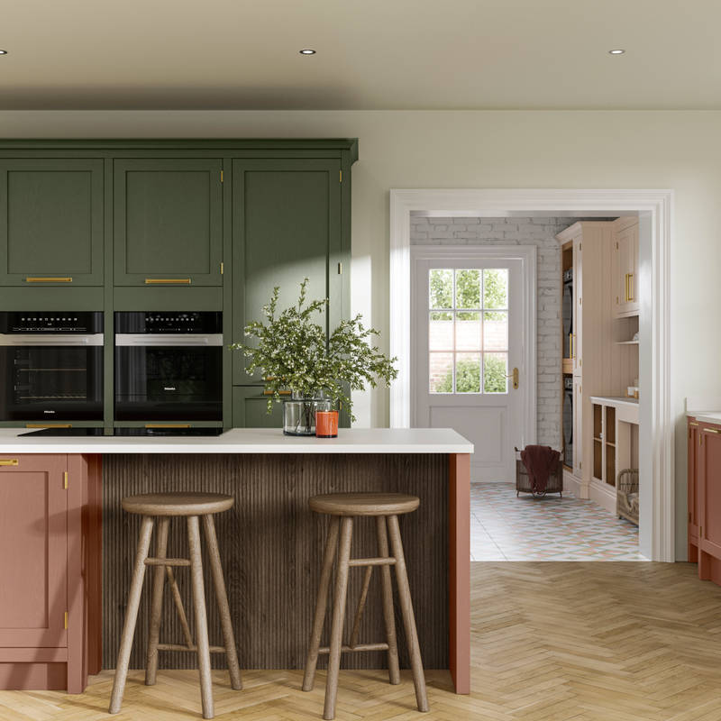 Tall Wardley kitchen cabinets  with built-in ovens, a kitchen island in shade Clay with wooden panelling by seating area and matching wooden bar stools.