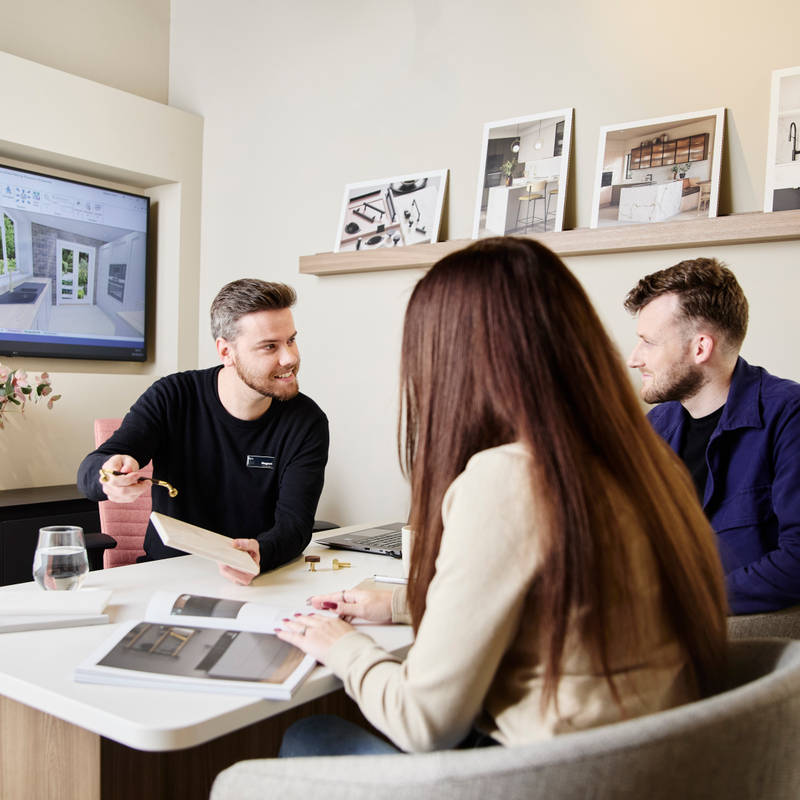 Magnet kitchen designer showing samples to customers in a Magnet store during consultation, woman browsing a brochure.