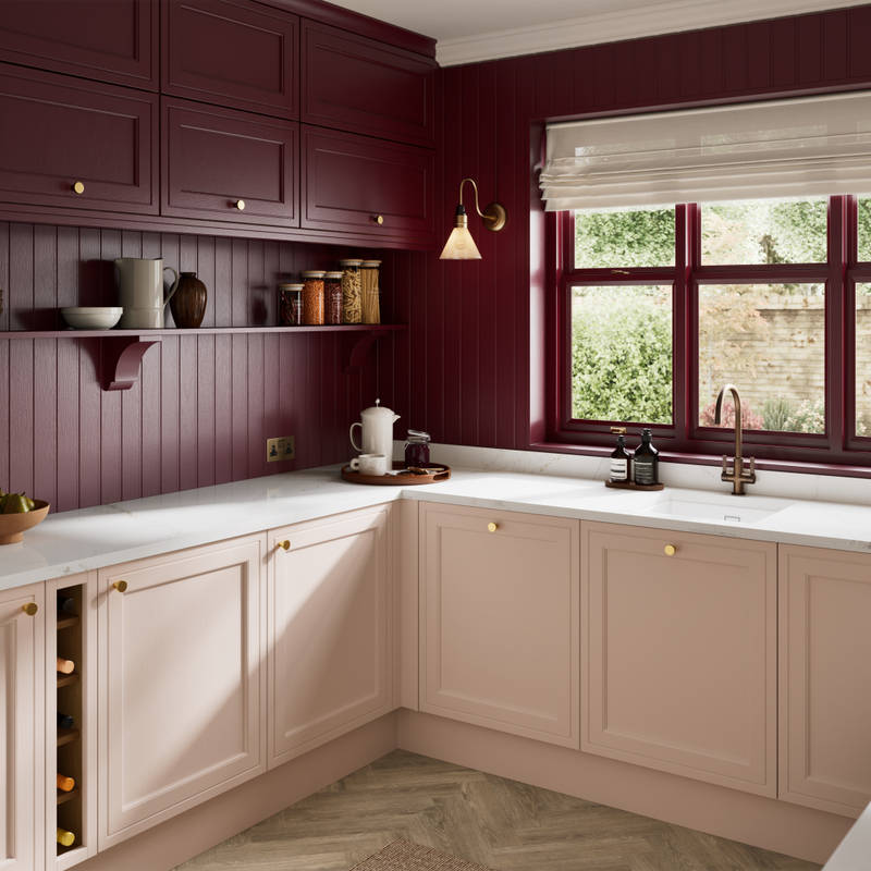 Painted wood grain Shaker style Bewdley kitchen with cabinets in light pink shade Chalk Blush, marbled worktop, brass knobs, red Morello wall-mounted cabinets with matching shelves and wall panel, built- in wine storage.