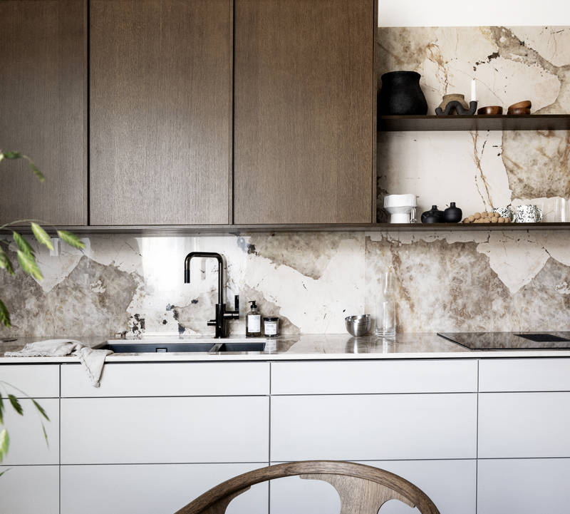 Køkken med en kombination af køkkenbord i beige Arkitekt Plus Sand med overskabe i Signatur Ekbacken fineret egetræslåge i brunbejdset fra Marbodal, bordplade og stænk, der matcher, og åbne væghylder i brunbejdset eg finer.