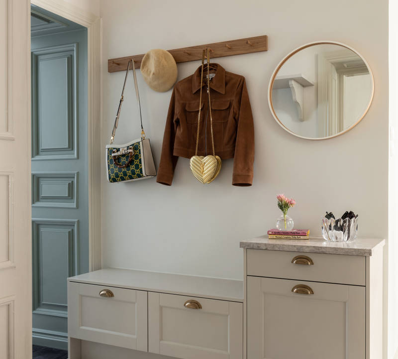 Hallskåp i Sandra Beijers lägenhet, lantliga luckan Fagerö i beige kulören Sand, låga skåp med knoppbräda och en spegel ovanför.