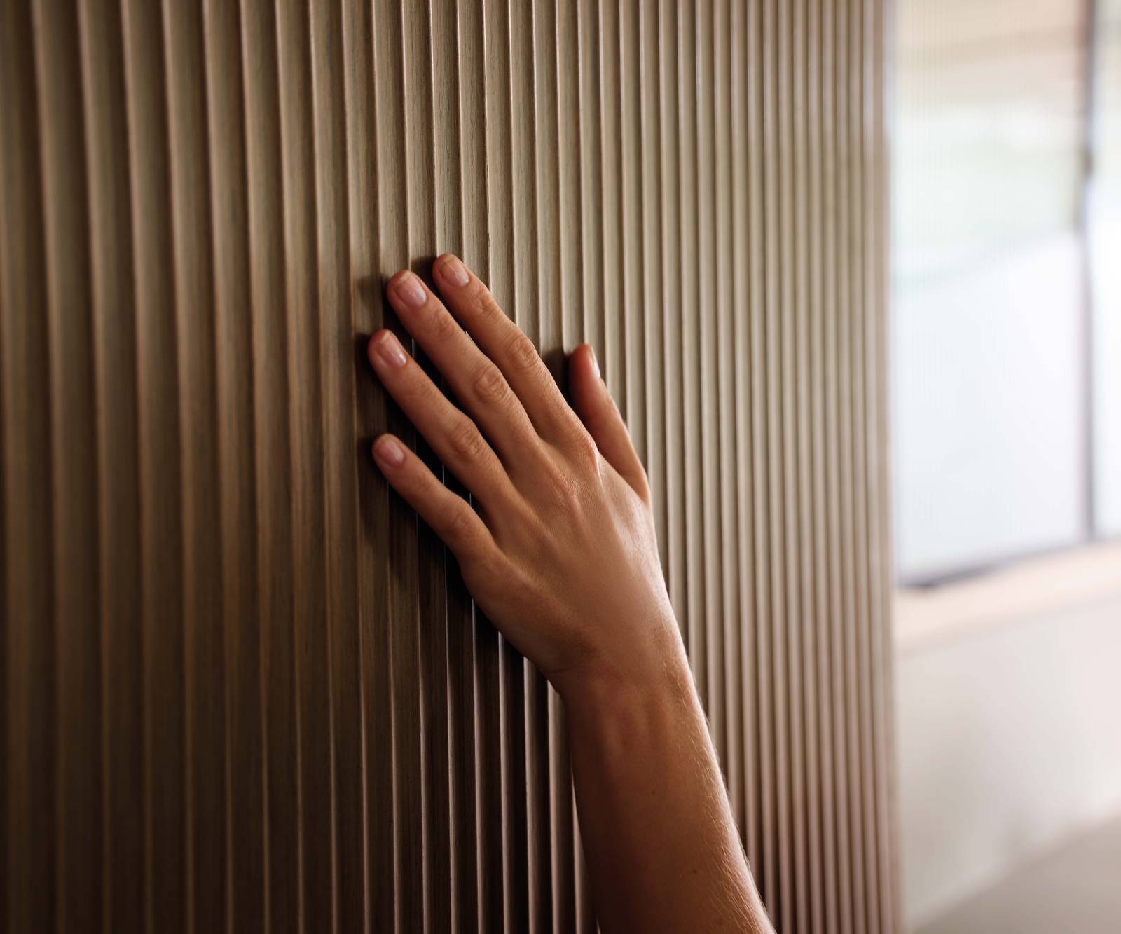 Close-up of hand touching the fluted wood fronts in Magnet's kitchen Nordic Nature.