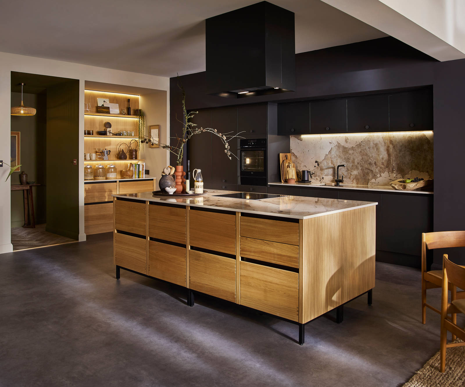 View of natural oak Nordic Craft kitchen island contrasting against the dark Sumi Black Hoxton cabinetry behind it.