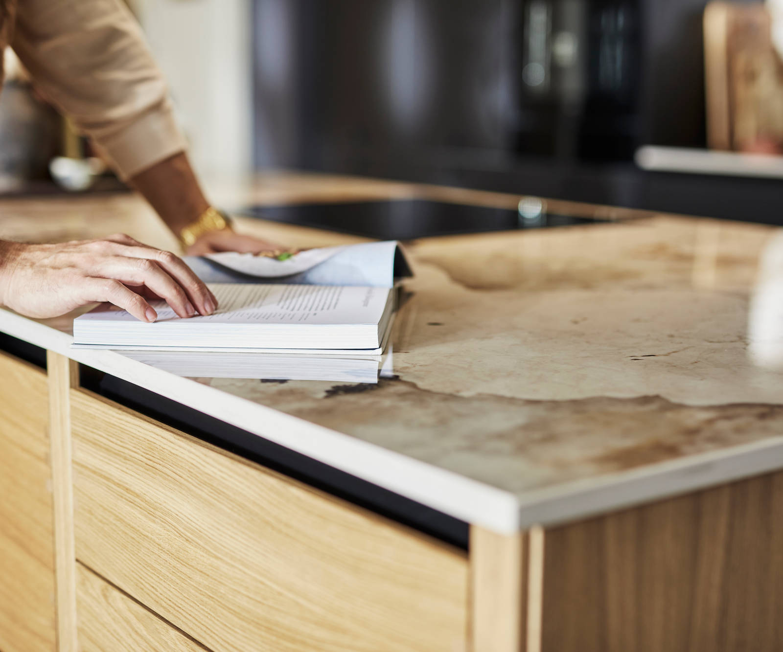 Close-up of Nordic craft kitchen island, with a beautiful marbled worktop as someone is checking a recipe in a cook book.