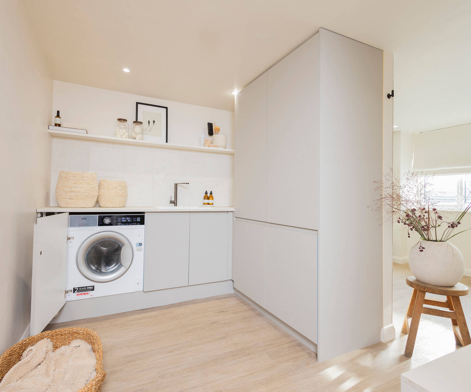 A utility room with cabinets with beige slab fronts in Yasmin Wyatt's calm and contemporary home with Luna Pebble from Magnet.