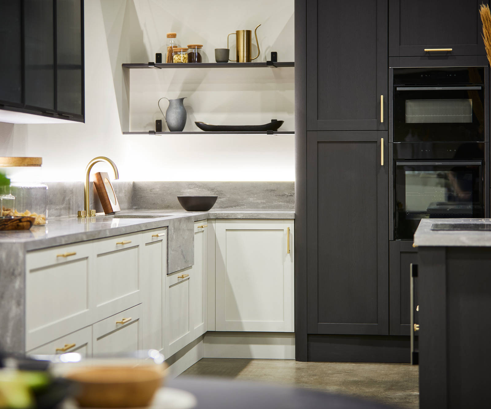 The Ambleside kitchen in Limestone and Graphite, paired with brass bar handles, a grey worktop and modern brass tap.