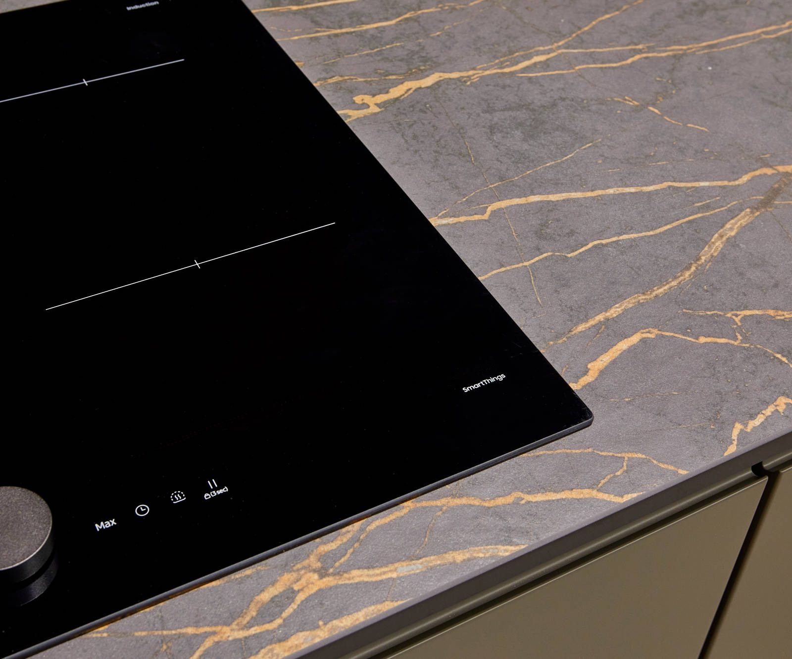 An organic marble-effect kitchen worktop, shown with modern Duxbury kitchen cabinets in Fawn, and black glass hob from SmartThings.