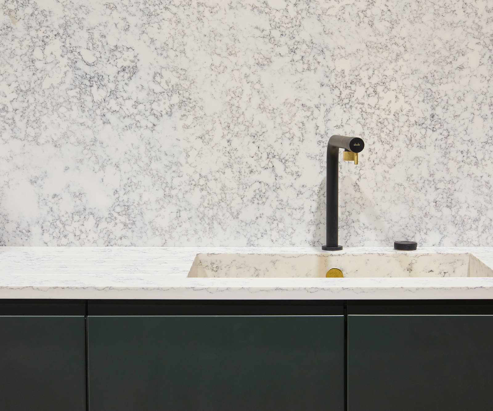 The Duxbury kitchen in rich green Arboretum, paired with white marble-effect worktops, built-in kitchen sink and a matte black and gold kitchen tap.
