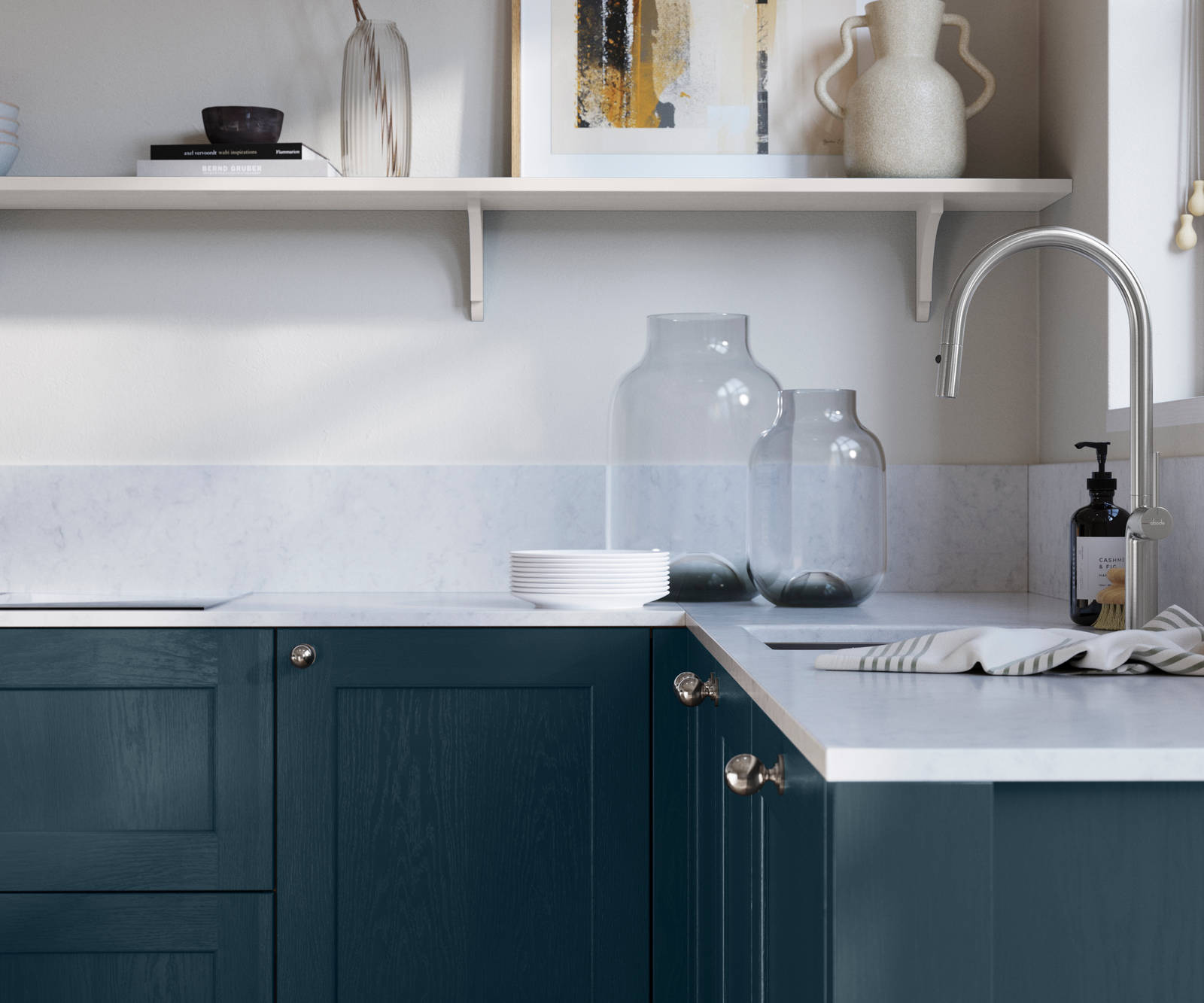 Ludlow, a traditional Shaker-style premium feel kitchen range with a visible woodgrain on its panelled doors here shown in the shade Voyage Blue styled with steel knobs, steel tap, a white marbled worktop with matching splashback.