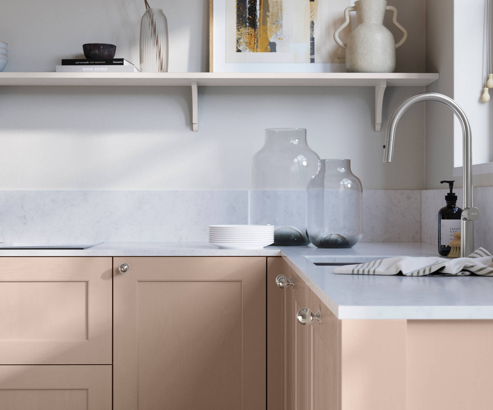 Ludlow, a traditional Shaker-style premium feel kitchen range with a visible woodgrain on its panelled doors here shown in the light pink shade Chalk Blush styled with steel knobs, steel tap, a white marbled worktop with matching splashback.
