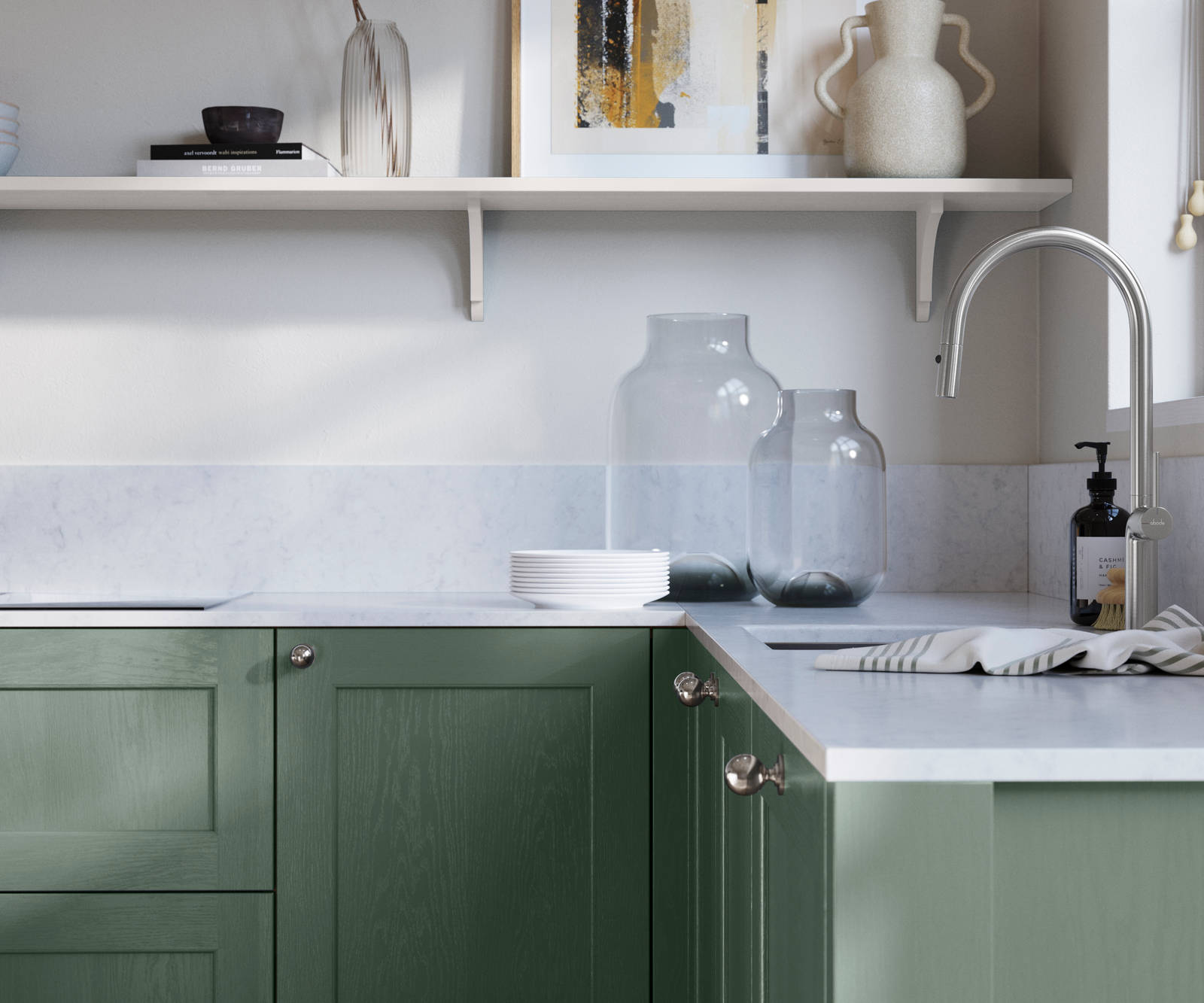 Ludlow, a traditional Shaker-style premium feel kitchen range with a visible woodgrain on its panelled doors here shown in the green shade Eucalyptus Green styled with steel knobs, steel tap, a white marbled worktop with matching splashback.
