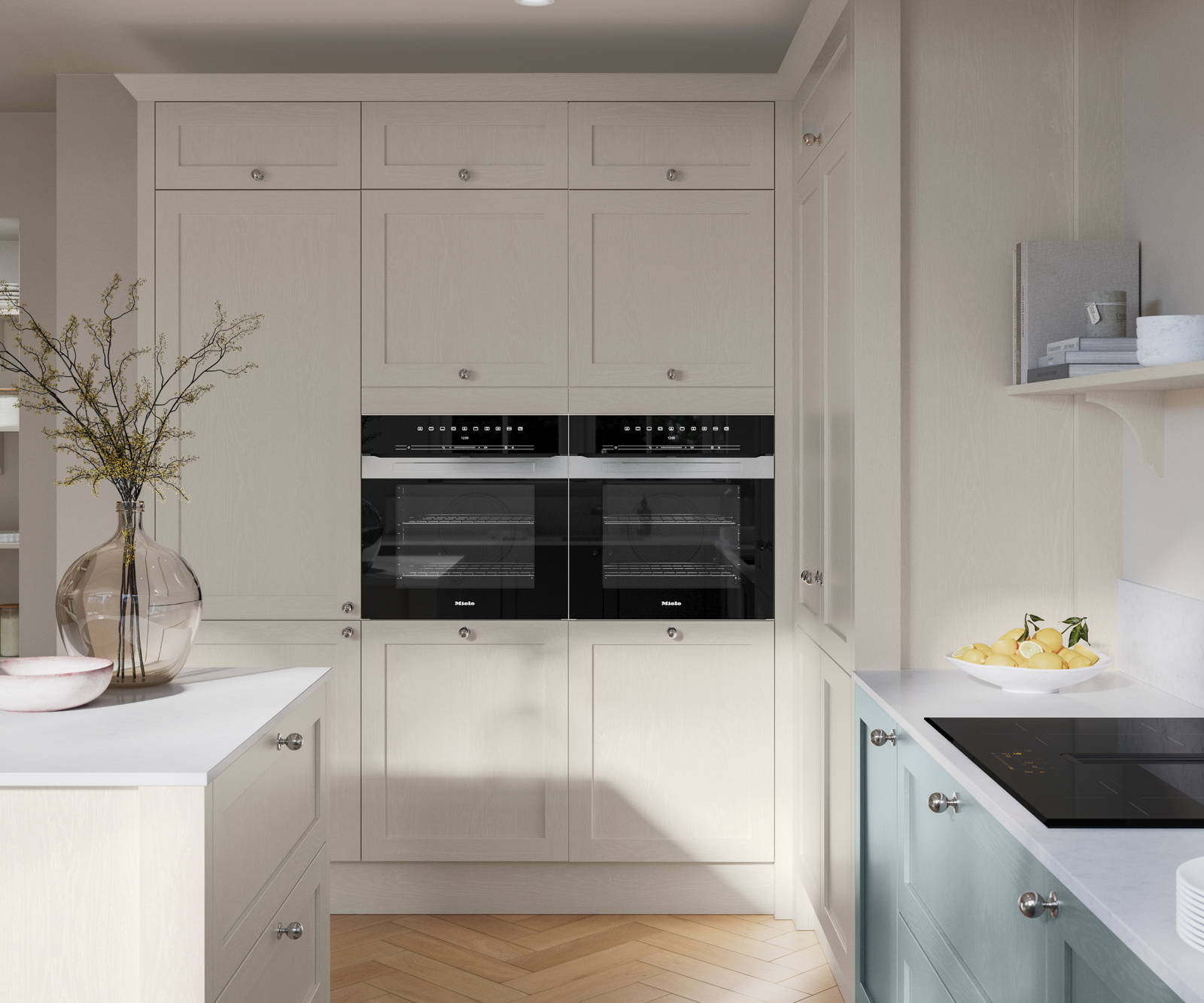 Tall Wardley Limestone cabinets with built-in ovens, steel knob handles, a white countertop on Limestone shade kitchen island and blue Duck Egg cabinets with induction hob.