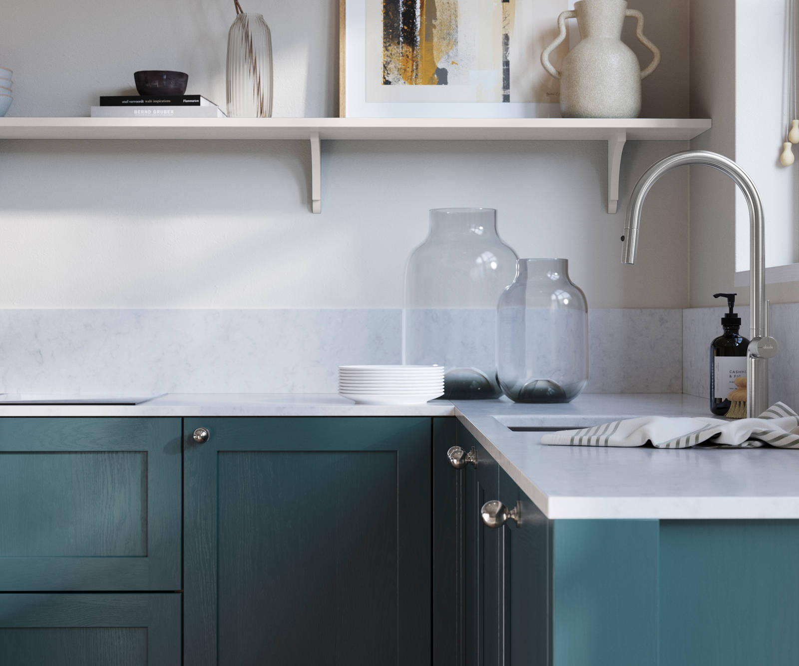 Wardley Carrington Blue kitchen cabinetry with steel knobs, steel tap, white marbled worktop and matching backsplash. An open shelf on the wall above cabinets with ceramics and a vase of flowers.