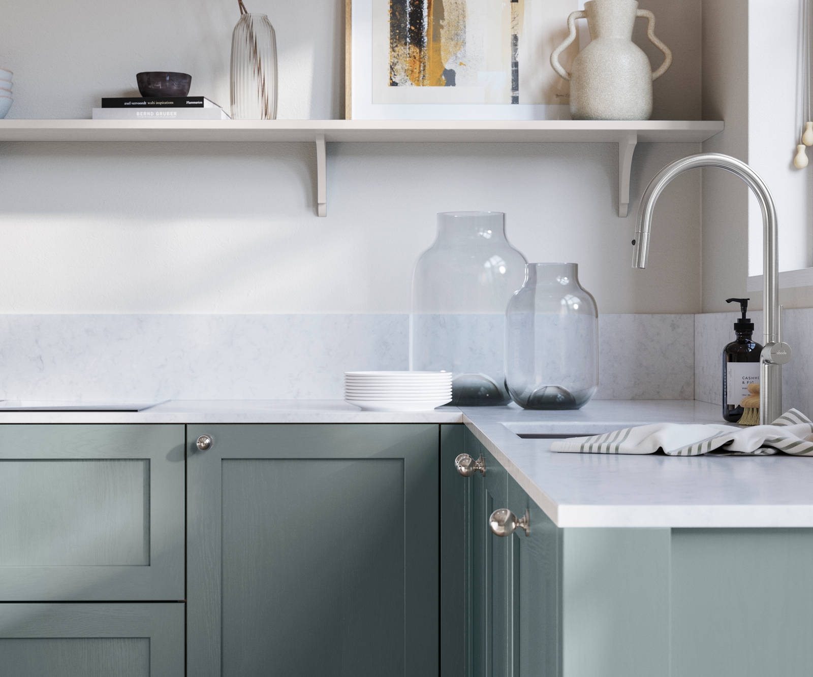 Wardley Duck Egg kitchen cabinetry with steel knobs, steel tap, white marbled worktop and matching backsplash. An open shelf on the wall above cabinets with ceramics and a vase of flowers.
