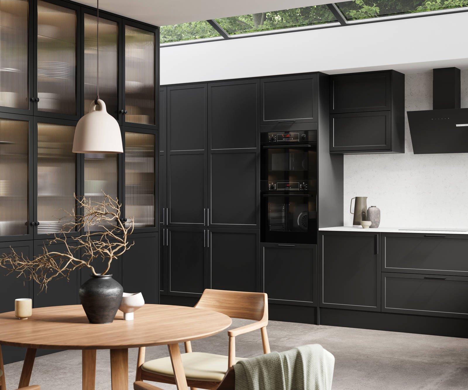 View of modern shaker kitchen Brunswick Sumi Black, with screen extractor over induction hob, tall fluted glass doorsvitrine cabinets, black frame skylights with wood dining table and chairs in foreground.