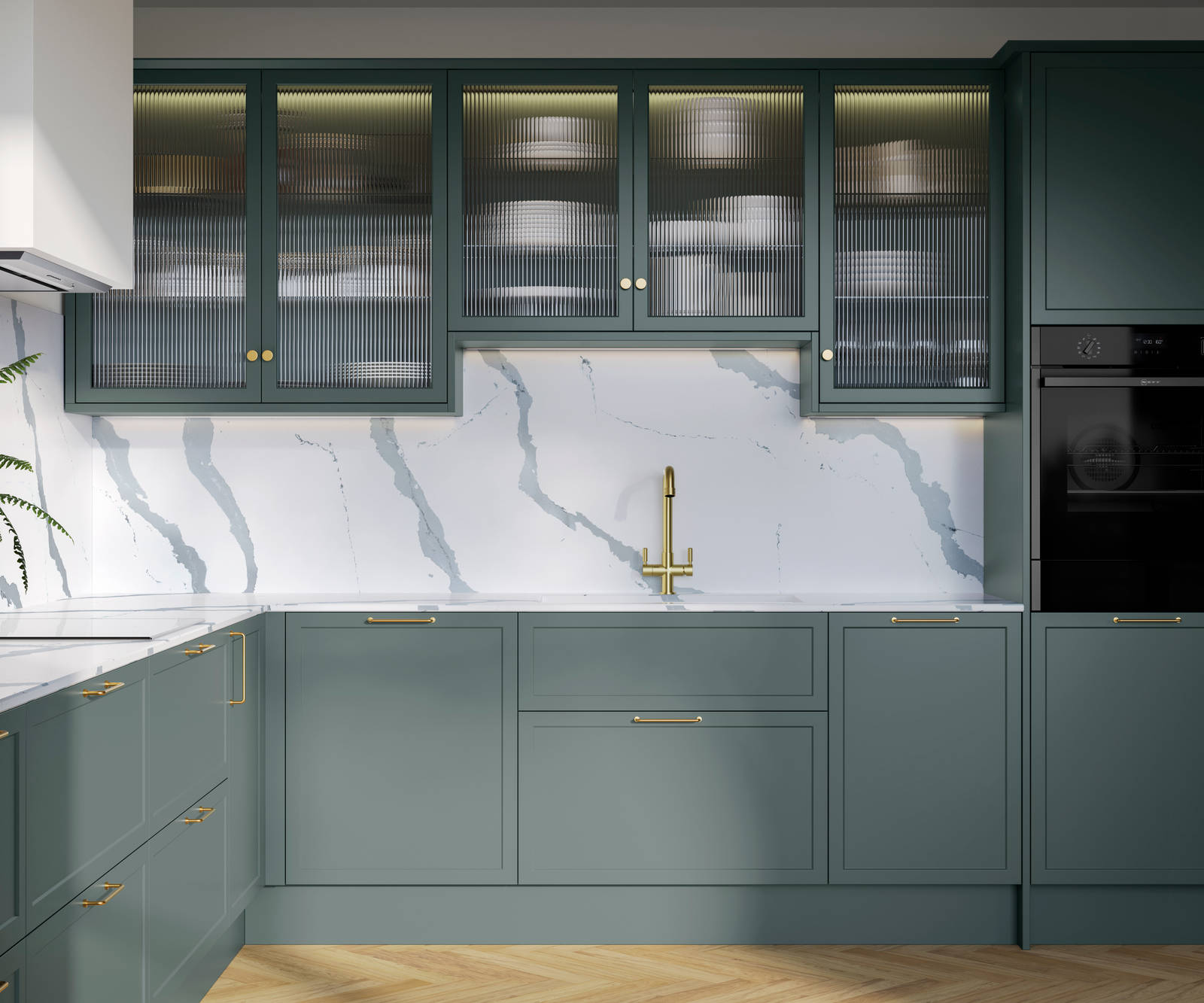 Modern Shaker kitchen Brunswick Spruce, a muted green shade, wall cabinets with fluted glass doors, Quartz Bianco Calacatta worktop and splashback, brass accessories like knobs, handles and tap, and a light wood herringbone floor.