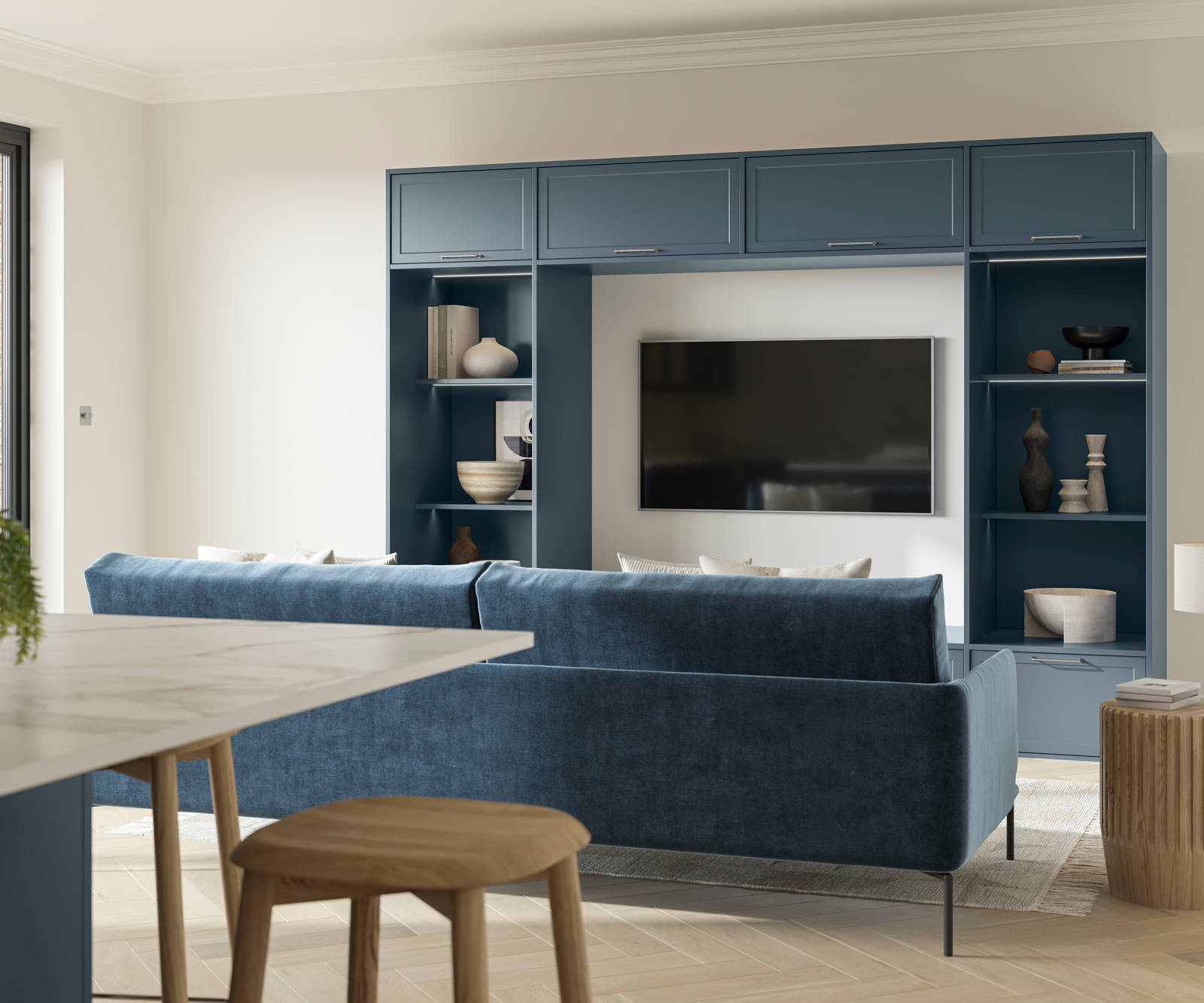 Cabinets and open shelves around a wall mounted TV in the modern Shaker range Brunswick Voyage Blue, matching blue counch and kitchen island in the foreground.