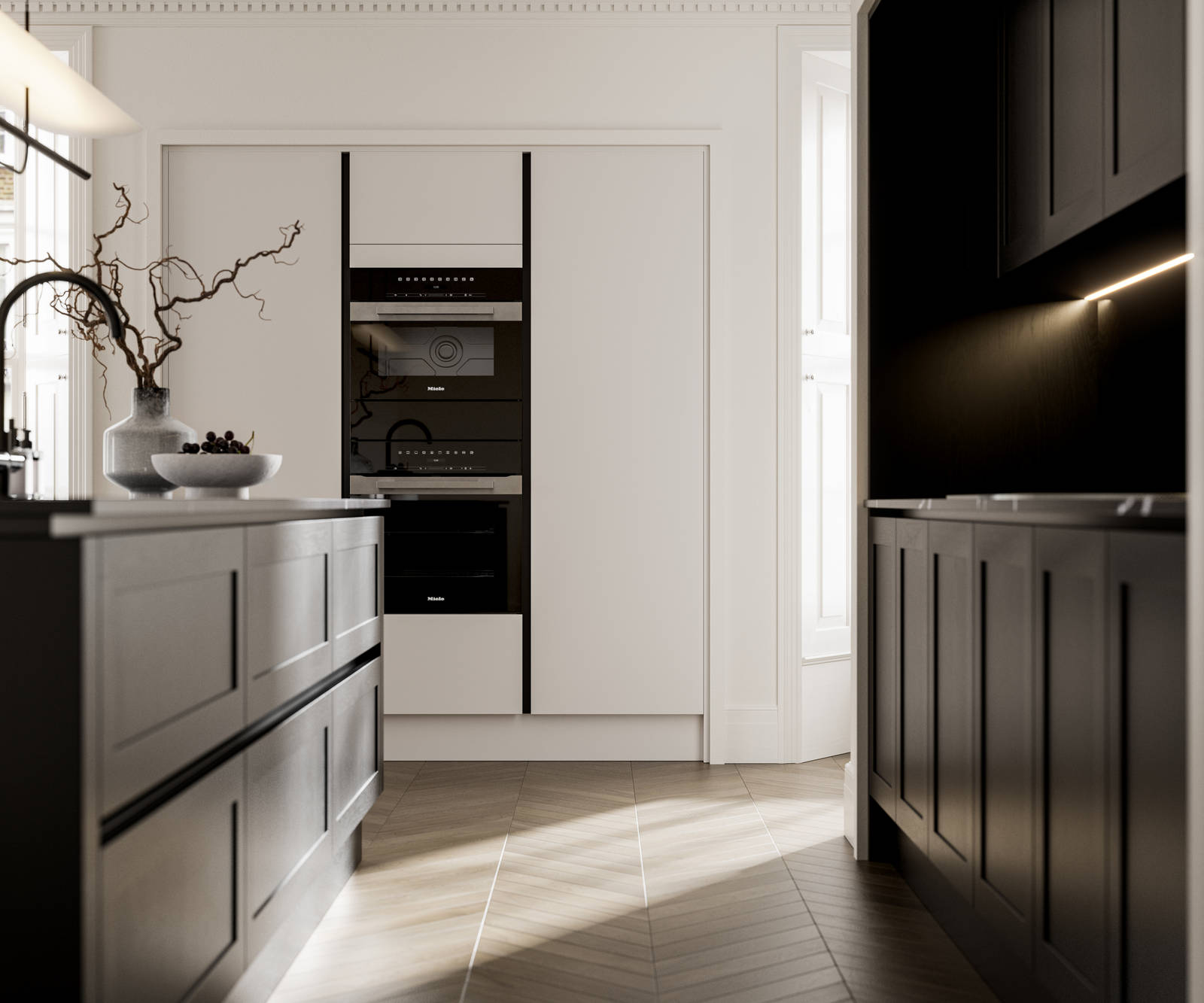 Handleless frame doors Integra Wardley Sumi black kitchen and kitchen island, Integra Soho Limestone tall cabinets with integrated ovens, natural shade ceramic vase holding foliage branches.