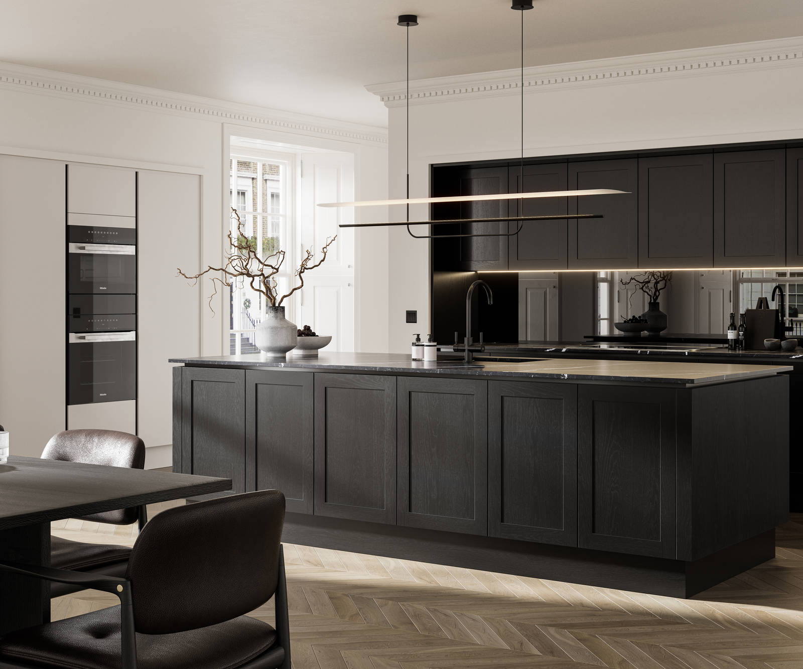 Handleless frame doors Integra Wardley Sumi black kitchen with kitchen island, Integra Soho Limestone tall cabinets with integrated ovens, black dining table and chairs, pale oak chevron flooring.